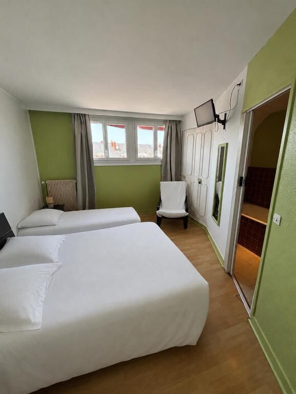 Twin beds and green wall in a room at Hôtel de la poste